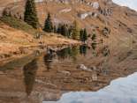 Le lac d'Engstlen reflète presque entièrement les chaînes de montagnes environnantes. Au premier plan, on aperçoit des rochers sous la surface de l'eau ; le paysage semble vaste et paisible.