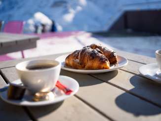 Deux tasses de café et deux croissants au chocolat sur une assiette.