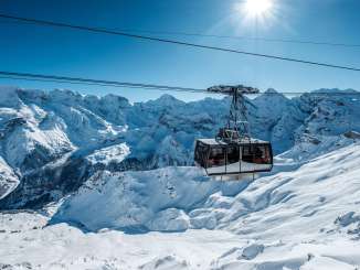 Die Schilthorn Gondel bei der Bergfahrt zur Birg. Im Hintergrund ist das verschneite Bergpanorama rund um das Gspaltenhorn zu sehen.