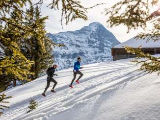 Two runners at the Winter Trail Running event in Grindelwald. The Eiger is visible in the background.