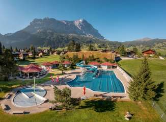 Das Freibad in Grindelwald aus der Vogelperspektive mit Häuser und Eiger im Hintergrund.
