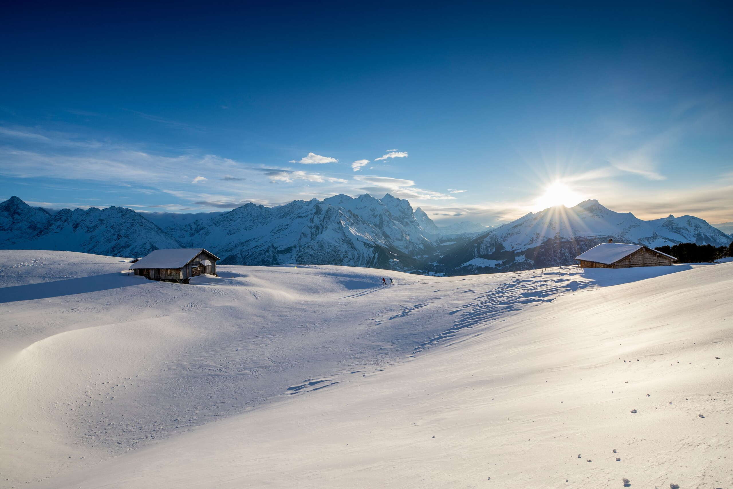 Zwei Wanderer*innen unterwegs inmitten der verschneite Winterlandschaft am Hasliberg