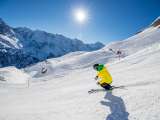 Ein Skifahrer zieht auf der Piste im Skigebiet Mürren-Schilthorn seine Kurven. Ein verschneites Bergpanorama ist im Hintergrund zu sehen.