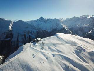 Aerial view of the mountain station and the Alpen Tower panoramic restaurant on Hasliberg in winter.