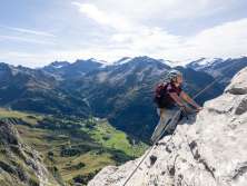 A woman on the Tälli via ferrata in the Haslital. She climbs along the rock face, well secured. The entire via ferrata offers a unique view.