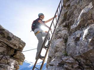 Eine Frau auf dem Klettersteig Tälli im Haslital. Unterwegs wird auf einer Leiter geklettert. Auf dem ganzen Klettersteig kann eine einmalige Aussicht genossen werden.