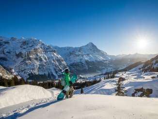 A snowboarder enjoys the view of the majestic mountain landscape from Grindelwald First.