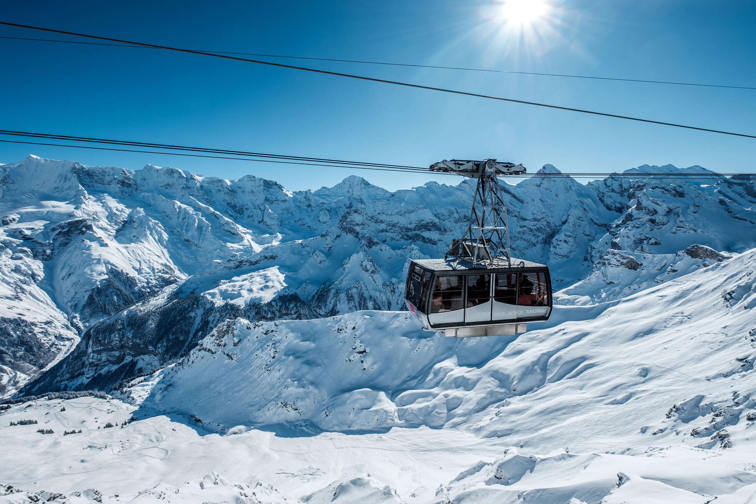 La télécabine du Schilthorn lors de la montée vers le Birg. En arrière-plan, on peut voir le panorama de montagnes enneigées autour du Gspaltenhorn.