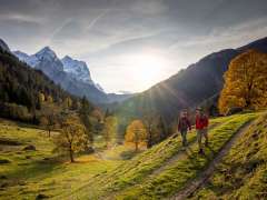Zwei Wanderer unterwegs in der Landschaft vom Rosenlauital. Es herrscht eine herbstliche Stimmung und der Himmel ist mit leichten Dunstwolken bedeckt. Das Bergpanorama hat einen verschneiten Umhang.