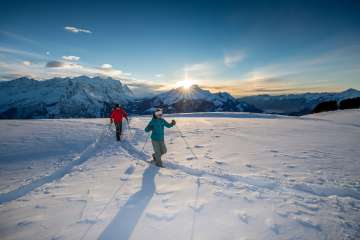 Au coucher du soleil, avec pour toile de fond un panorama montagneux impressionnant : deux randonneurs en raquettes sur le Hasliberg