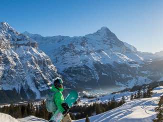 Ein Snowboarder geniesst die Aussicht über die imposante Bergwelt auf Grindelwald First.