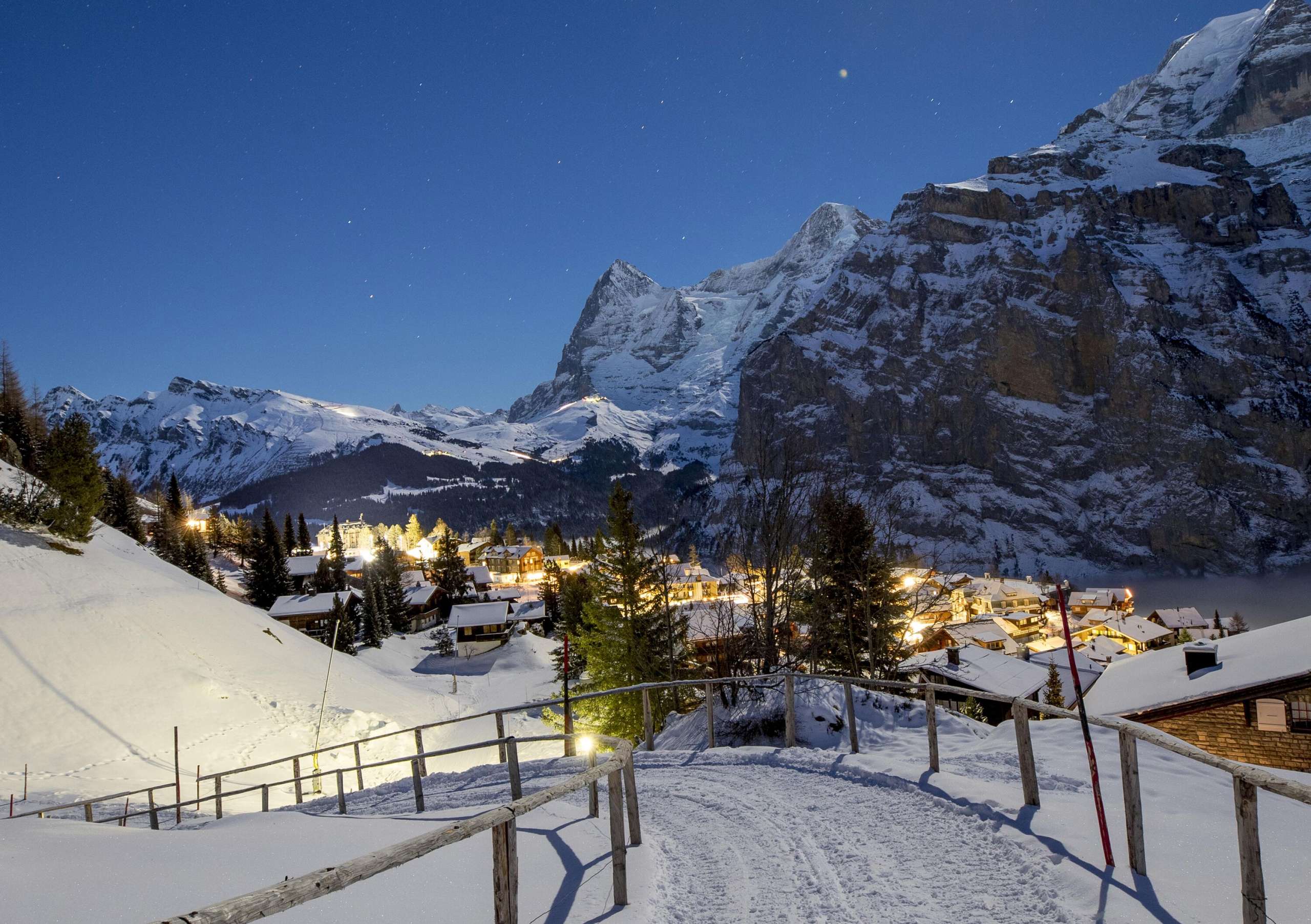 Promenade enneigée à Mürren la nuit. Le sentier offre une vue sur l'Eiger, le Mönch et la Jungfrau.