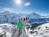 Les touristes profitent de la vue hivernale depuis le belvédère du First Cliff Walk. À l'arrière-plan, l'Eiger enneigé s'étend à l'horizon.