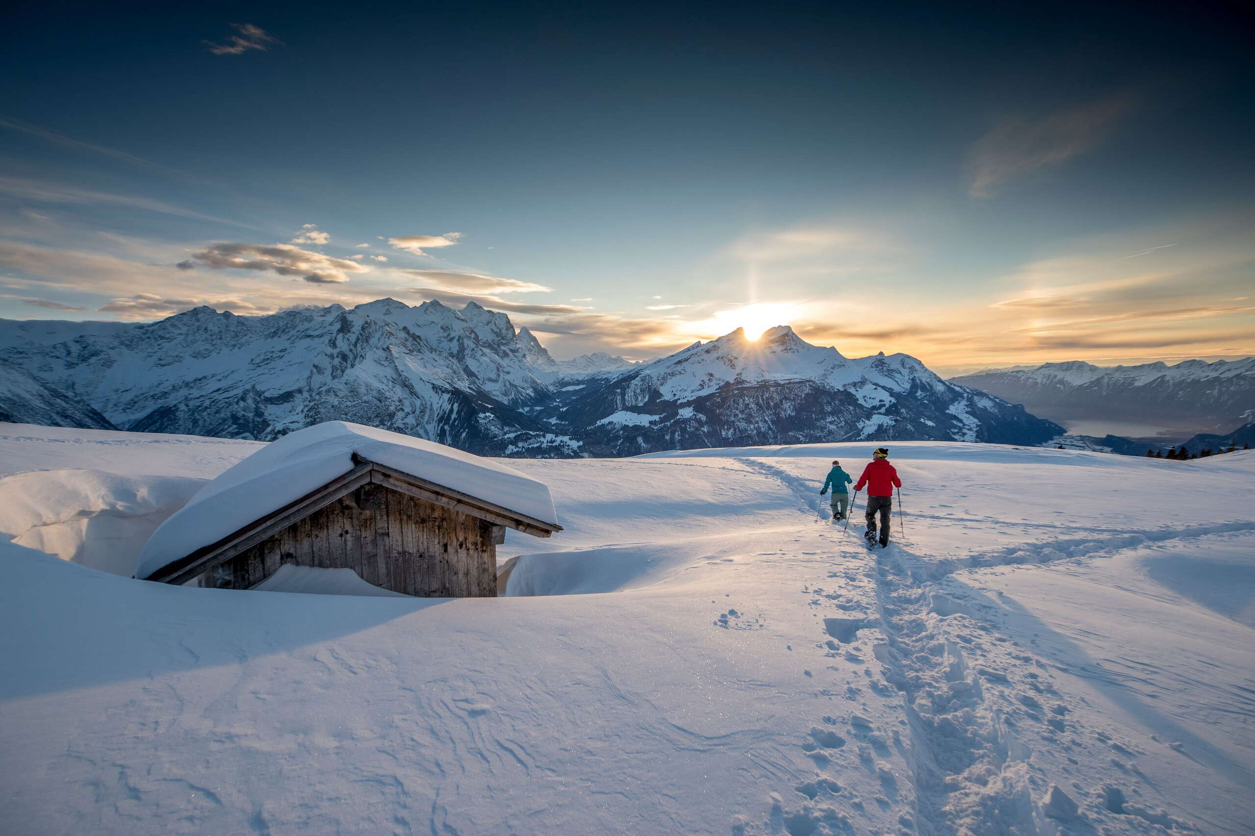 Im Sonnenuntergang - und vor eindrücklicher Bergkulisse: Zwei Schneeschuhläufer*innen unterwegs am Hasliberg