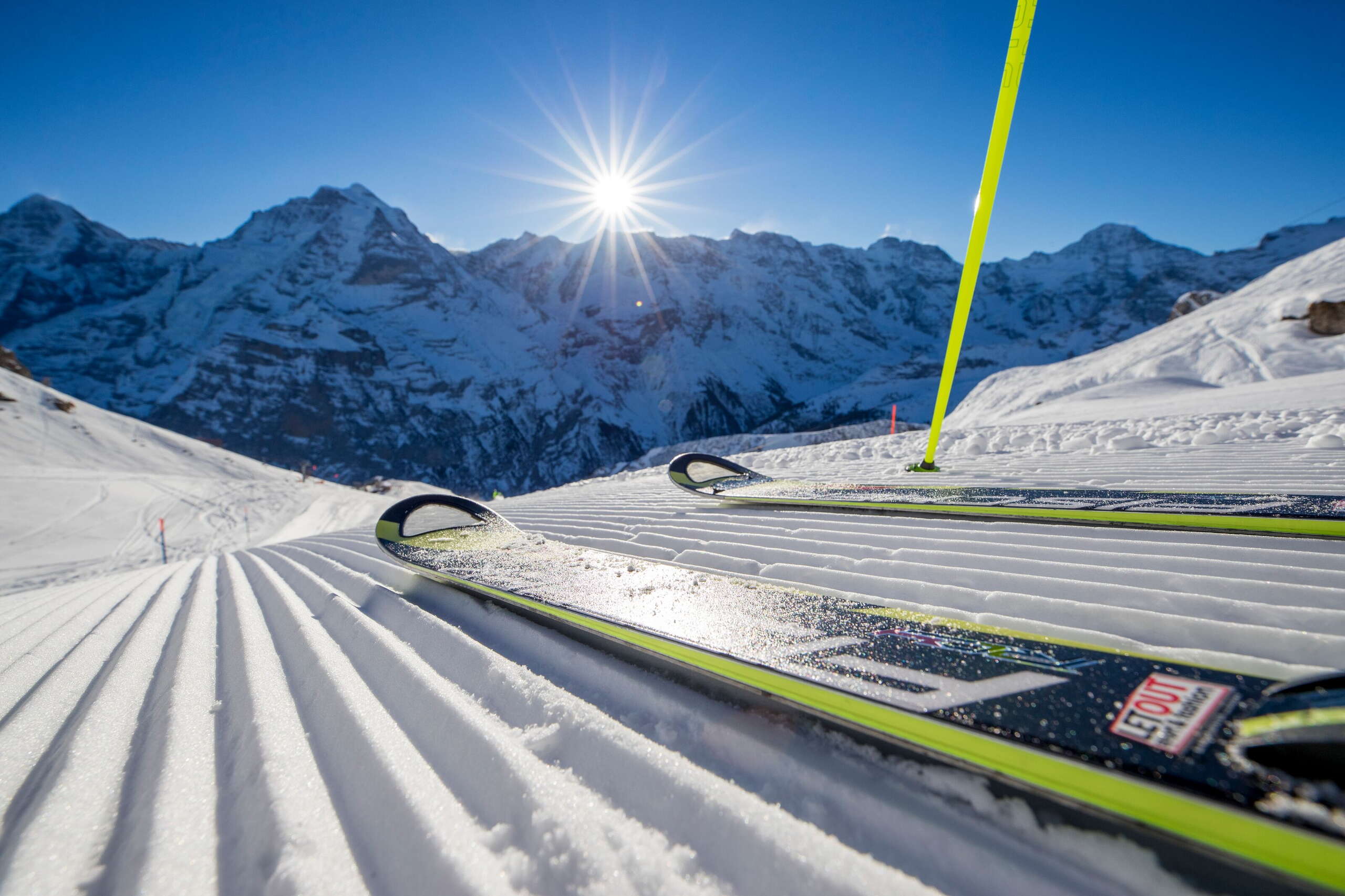 Skier posieren auf der Piste in Mürren-Schilthorn. Das Dreigestirn Eiger, Mönch und Jungfrau ist aus der Ferne zu sehen.