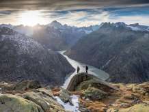 Two hikers out and about in the Grimsel region. They are hiking with a breathtaking view of a reservoir in the Grimsel region.