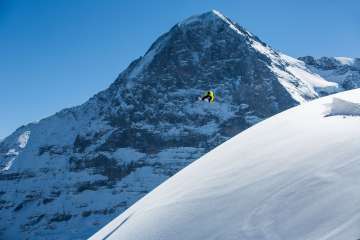 Snowboarding at the Grindelwald First ski resort. Jumps in fresh powder snow with the Eiger in the background.