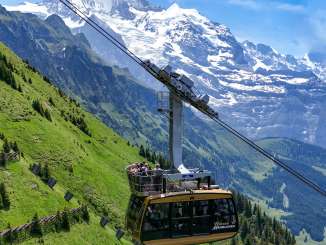 Le téléphérique Wengen–Männlichen monte en survolant des prairies alpines escarpées. En arrière-plan, l'impressionnant paysage de haute montagne se détache, soulignant l'emplacement spectaculaire de la ligne.
