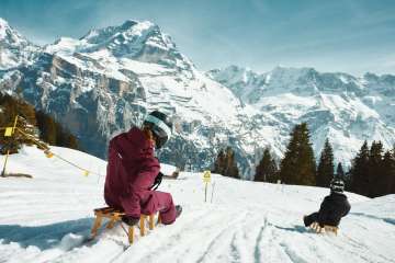 Zwei Personen sind mit dem Schlitten auf dem Bob Run in Mürren unterwegs.