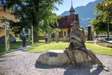 Vor dem Sherlock Holmes Museum in Meiringen steht eine Statue vom Meister-Dedektiv. Die Touristen lesen sich in die Geschichte von Sherlock Holmes ein.