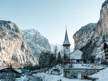 The church in the village of Lauterbrunnen in winter. The Staubbach Falls are visible in the background.