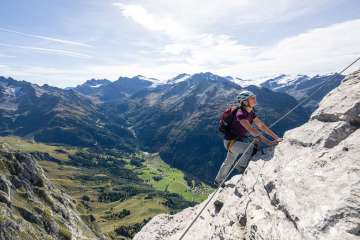 Eine Frau auf dem Klettersteig Tälli im Haslital. Gut gesichert wird dem Felsen entlang geklettert. Auf dem ganzen Klettersteig kann eine einmalige Aussicht genossen werden.