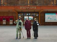 Drei Wintersportler*innen mit Skiern in der Schilthornbahnstation Stechelberg vor dem Eingang der Talstation.