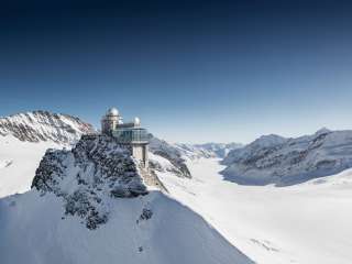 Luftaufnahme des Jungfraujoch im Winter. Im Hintergrund ist neben dem Bergpanorama der Aletschgletscher zu sehen.