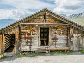 Une petite cabane dans les alpages de la Forêt-Noire, avec des géraniums sur la façade. La porte est ouverte.