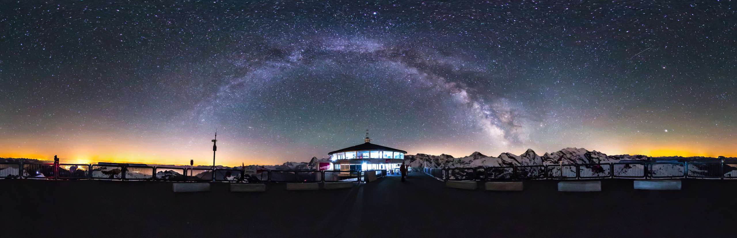 Le restaurant Schilthorn de nuit, entouré d'obscurité avec des restes de couchant à l'horizon et des étoiles dans le ciel.
