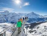 Die Touristen geniessen die winterliche Aussicht vom First Cliff Walk Aussichtspunkt. Im Hintergrund erstreckt sich der verschneite Eiger am Horizont.