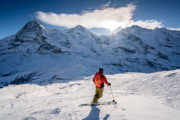 Le ski dans le domaine skiable de Grindelwald - Wengen. Le skieur fait une pause et admire le panorama sur le trio des sommets : l'Eiger, le Mönch et la Jungfrau.