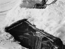 Winternostalgie in Mürren. Eine Frau gönnt sich eine Pause im Liegestuhl auf dem verschneiten Dach einer Alphütte.