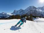A skier on the ski cross course at the Mürren-Schilthorn ski resort. The Eiger, Mönch, and Jungfrau mountain trio can be seen in the distance.