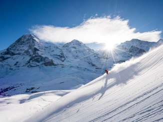 Le ski dans le domaine skiable de Grindelwald-Wengen. Les skieurs tracent leurs traces dans la neige en effectuant de magnifiques virages. En arrière-plan, on aperçoit le trio de sommets formé par l'Eiger, le Mönch et la Jungfrau.