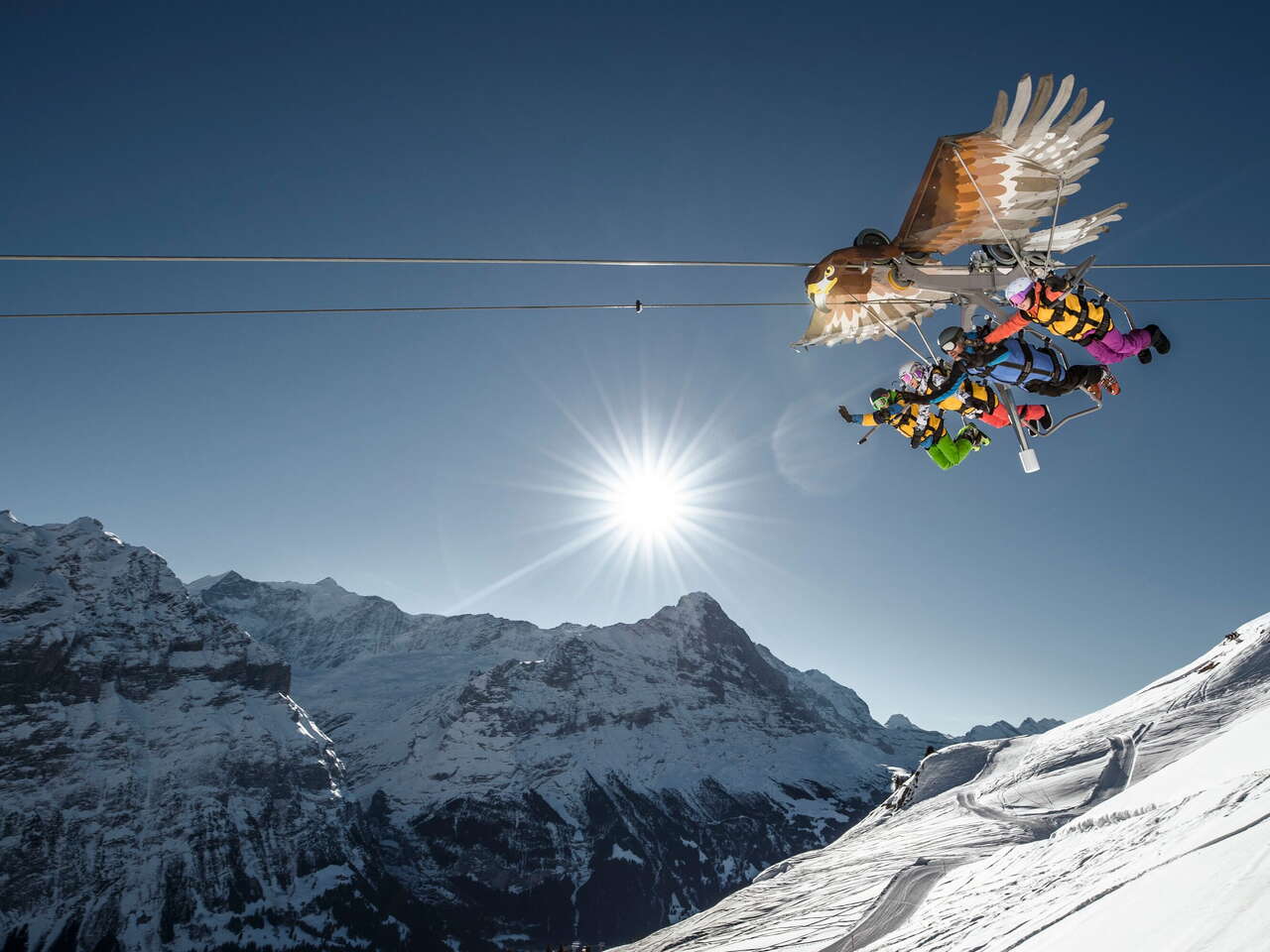 Le First Glider dévale la montagne à toute vitesse. En arrière-plan, le soleil brille au-dessus de l'Eiger enneigé.