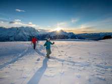 Im Sonnenuntergang - und vor eindrücklicher Bergkulisse: Zwei Schneeschuhläufer*innen unterwegs am Hasliberg