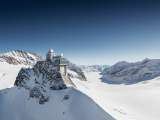 Vue aérienne du Jungfraujoch en hiver. À l'arrière-plan, on aperçoit le glacier d'Aletsch, avec le panorama montagneux en toile de fond.