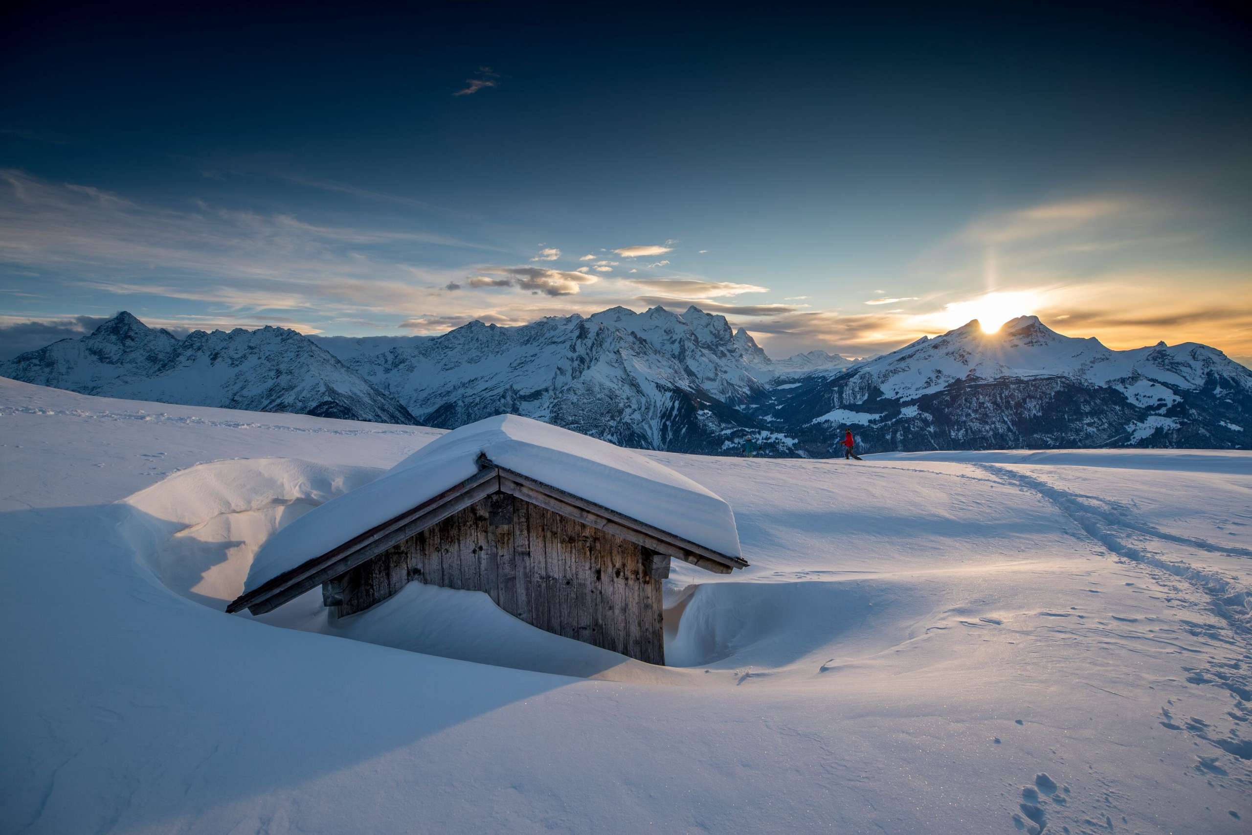 Ein einsamer Wanderer unterwegs bei Sonnenuntergang  in der verschneite Winterlandschaft am Hasliberg
