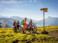 Die Biker schauen auf den Wegweiser und geniessen die Aussicht vom Hasliberg. Die Aussicht bietet einen sommerlichen Blick über die Berglandschaft.